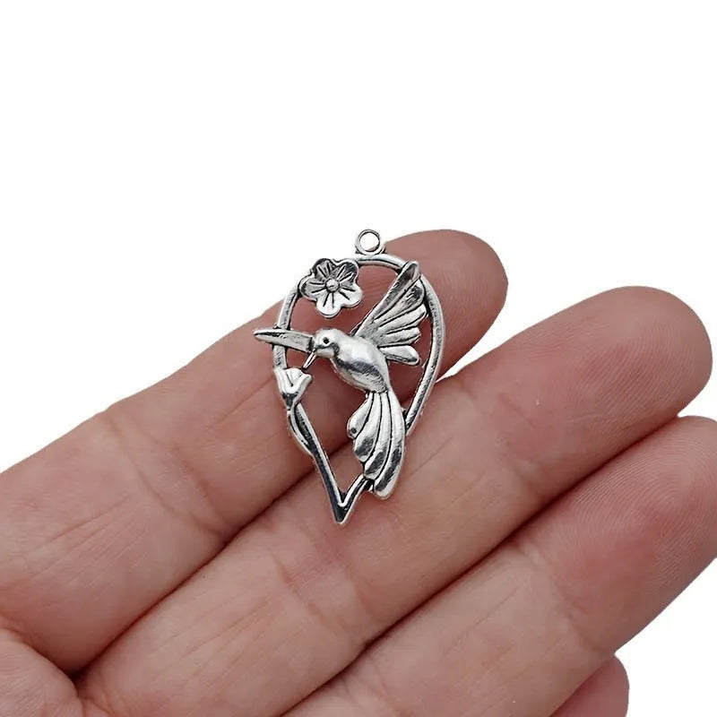 Close-up of an alloy pendant charm featuring a detailed magpie or cuckoo bird design with an electroplated finish.