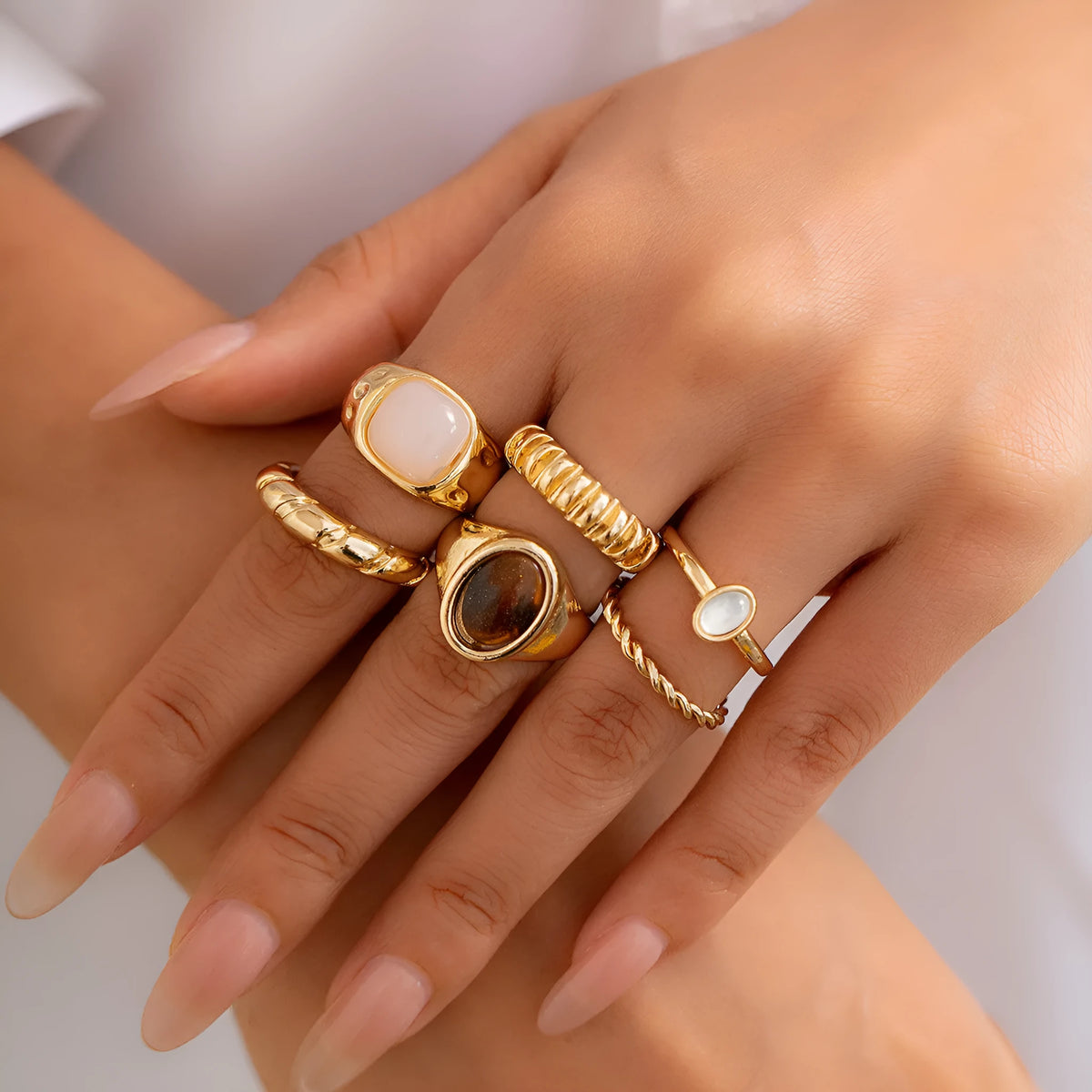 Six geometric alloy rings in light gold finish arranged for display