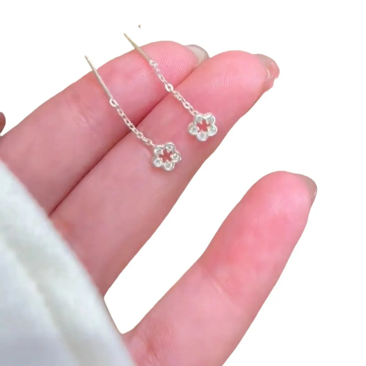A pair of silver-coloured alloy hanging earrings with a hollow floral stud design.
