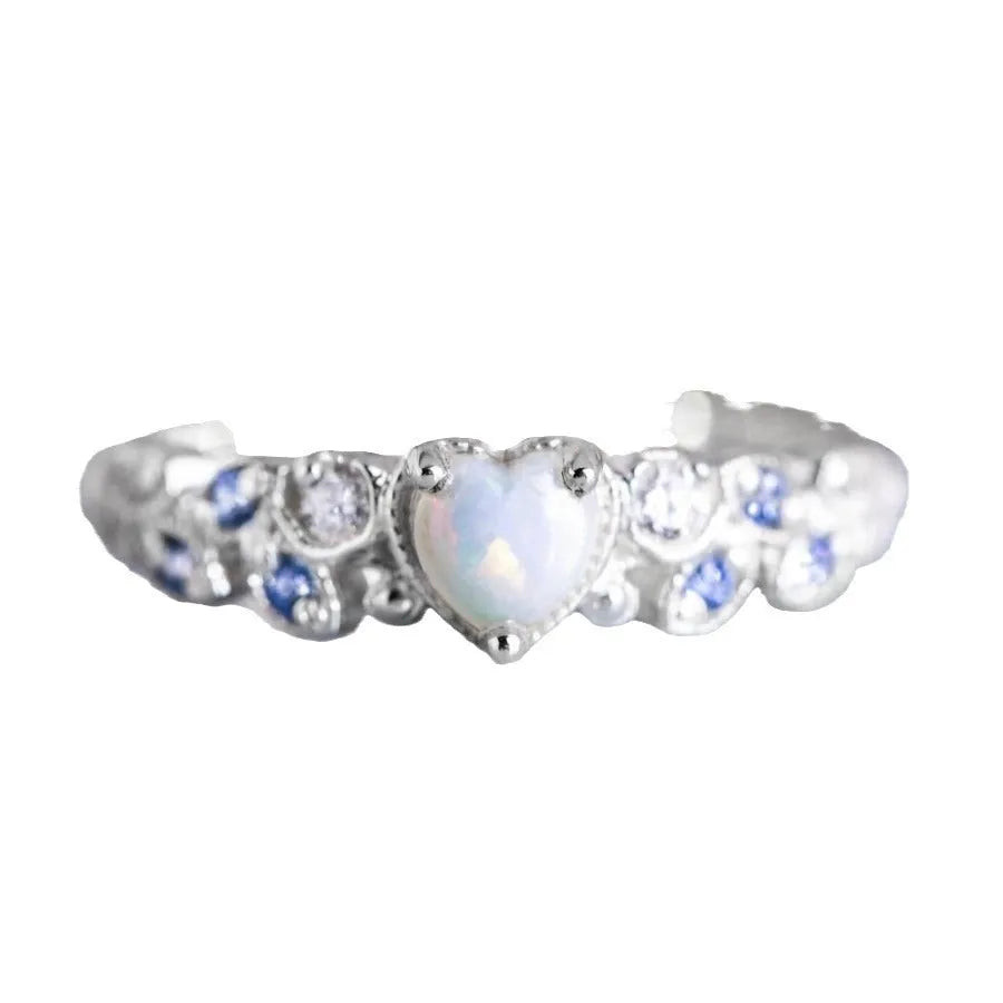 Women's white alloy heart ring with floral opal ocean detailing, shown on a finger.