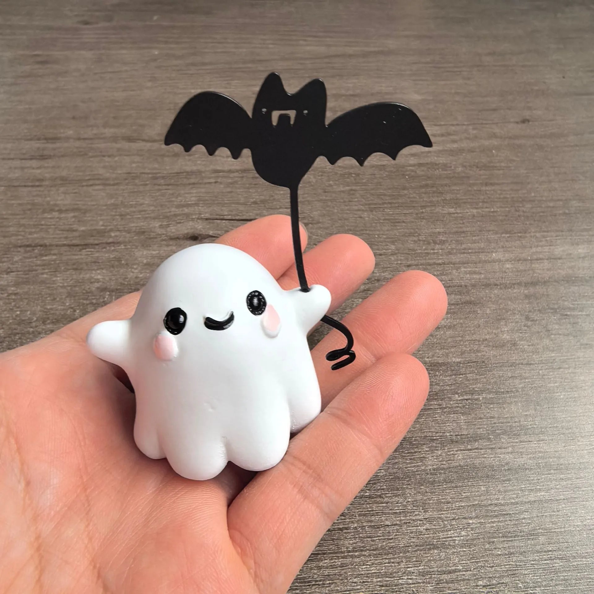 Small resin Halloween statue of a ghost walking a dog and holding a bat.