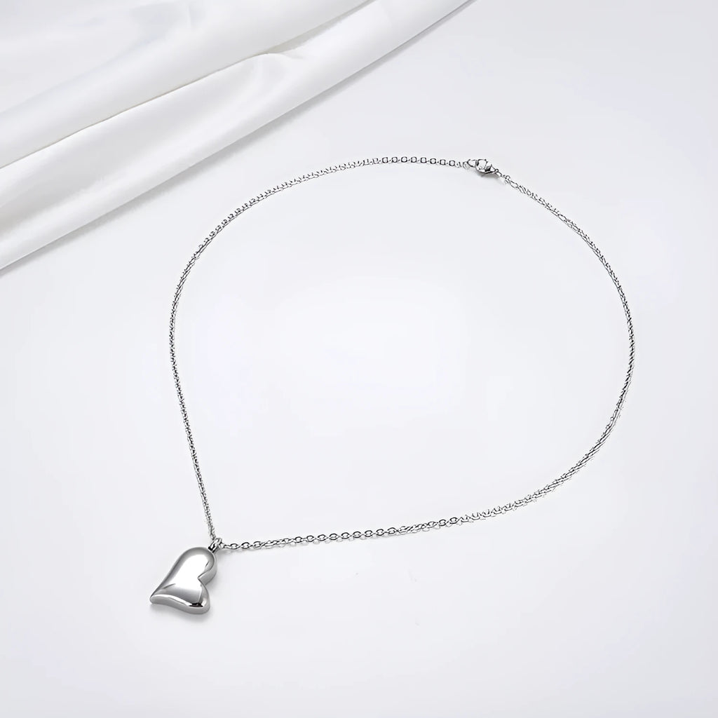 Silver-colour stainless steel necklace with a curved peach heart pendant on an adjustable chain.