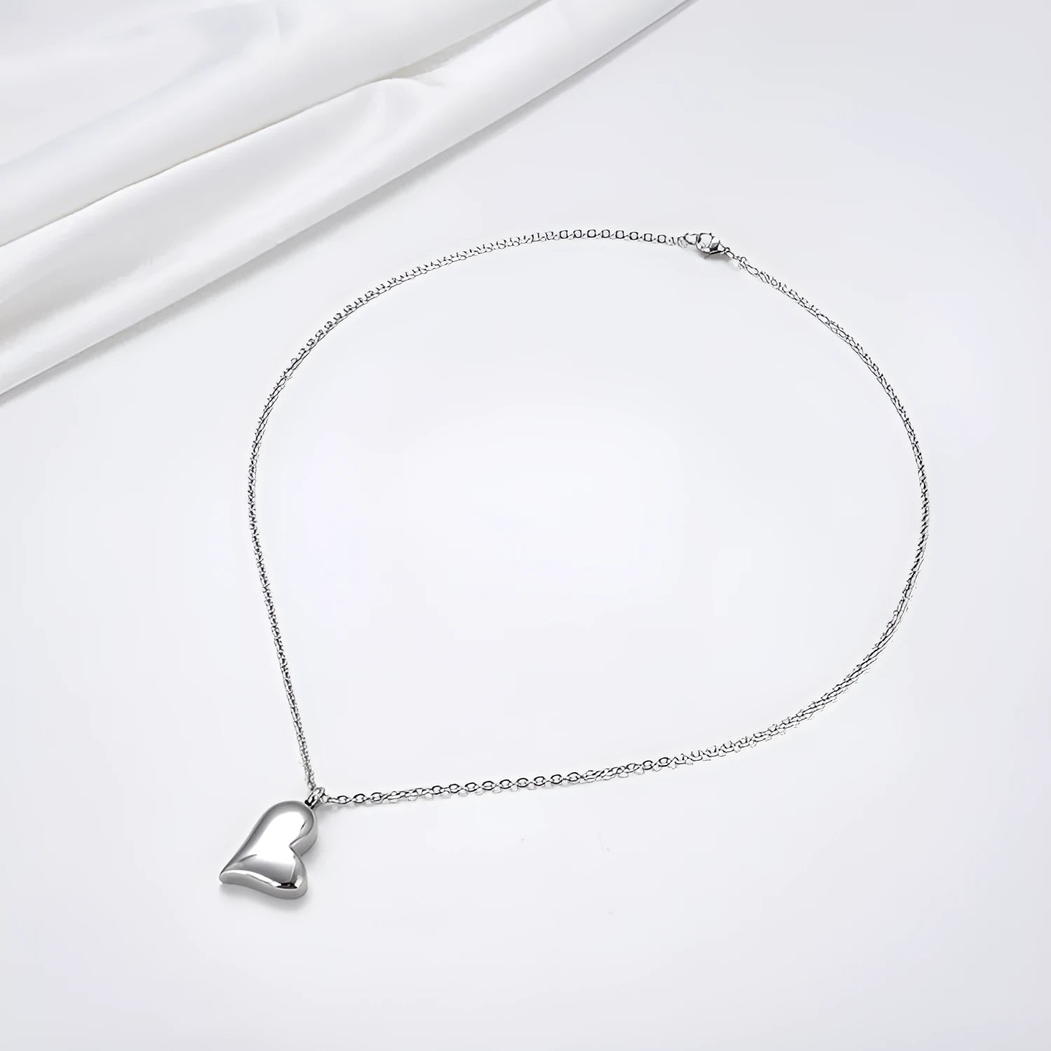 Silver-colour stainless steel necklace with a curved peach heart pendant on an adjustable chain.