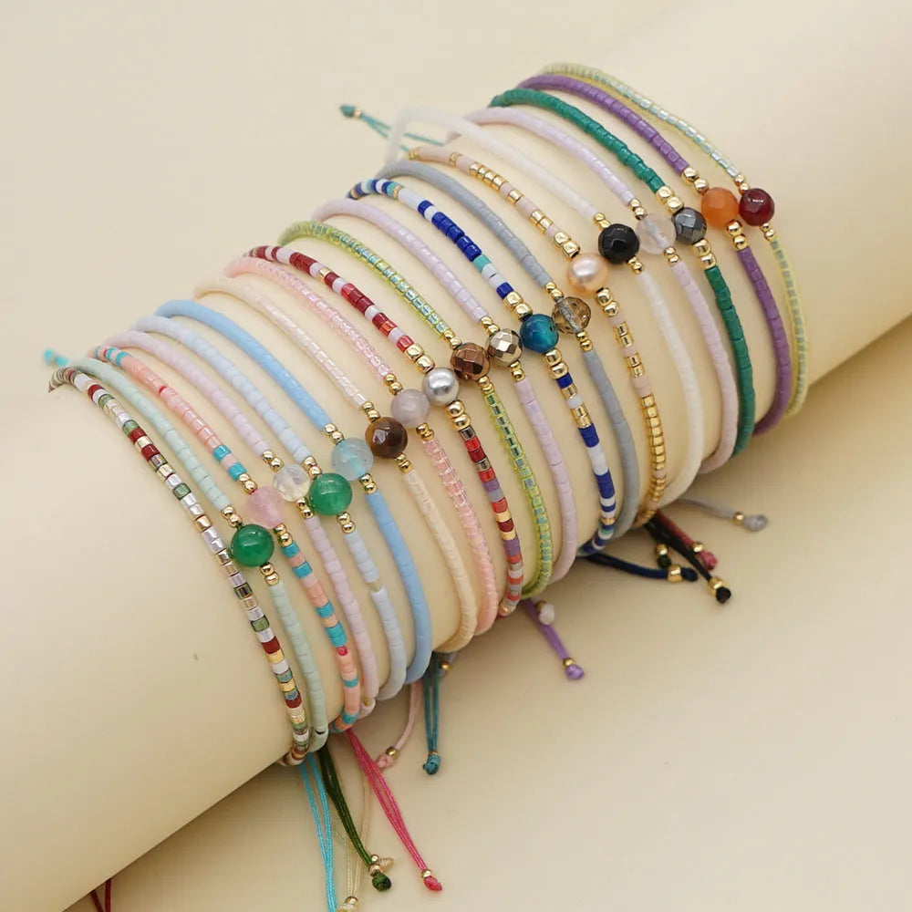 Close-up of a colourful handmade Bohemian bracelet with semi-precious stone and glass geometry beads on a wrist.