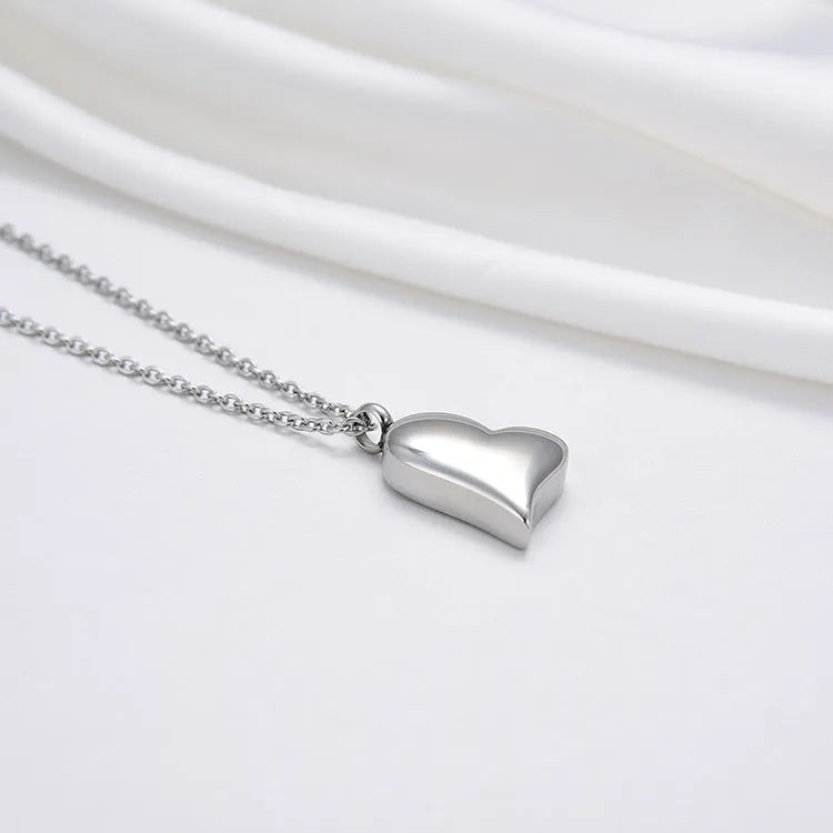 Silver-colour stainless steel necklace with a curved peach heart pendant on an adjustable chain.