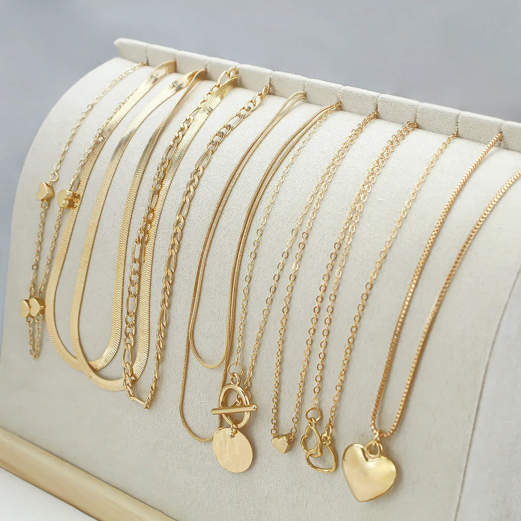 Ten gold-coloured women's necklaces with different alloy pendants on snake bone chains