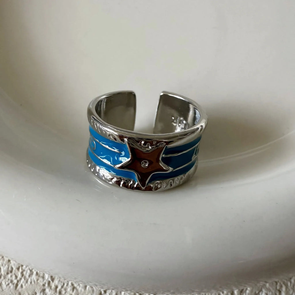 Adjustable distressed geometric ring with line design in electroplated black, blue, or red.