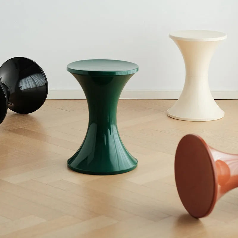 Plastic hourglass-style shoe changing stool in green, shown in a home entryway.