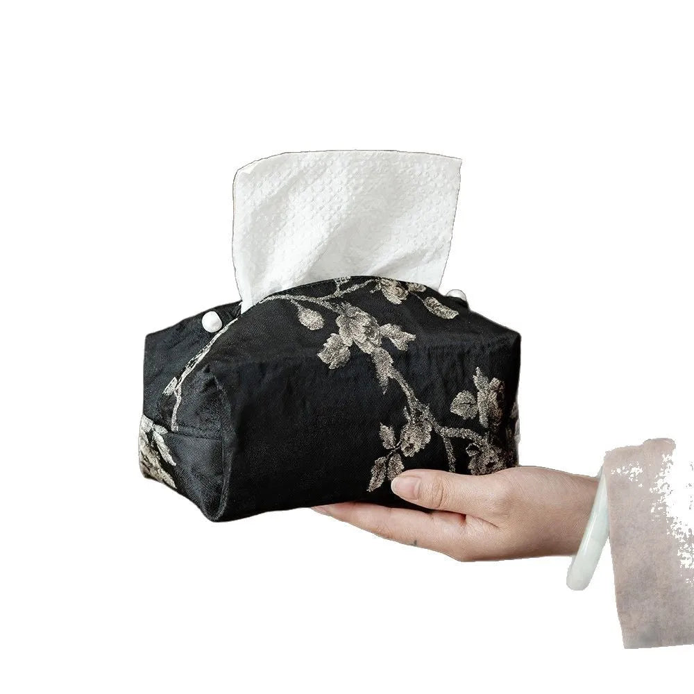 White Chinese brocade tissue box cover with embroidered plum blossoms, shown with and without a pearl buckle.