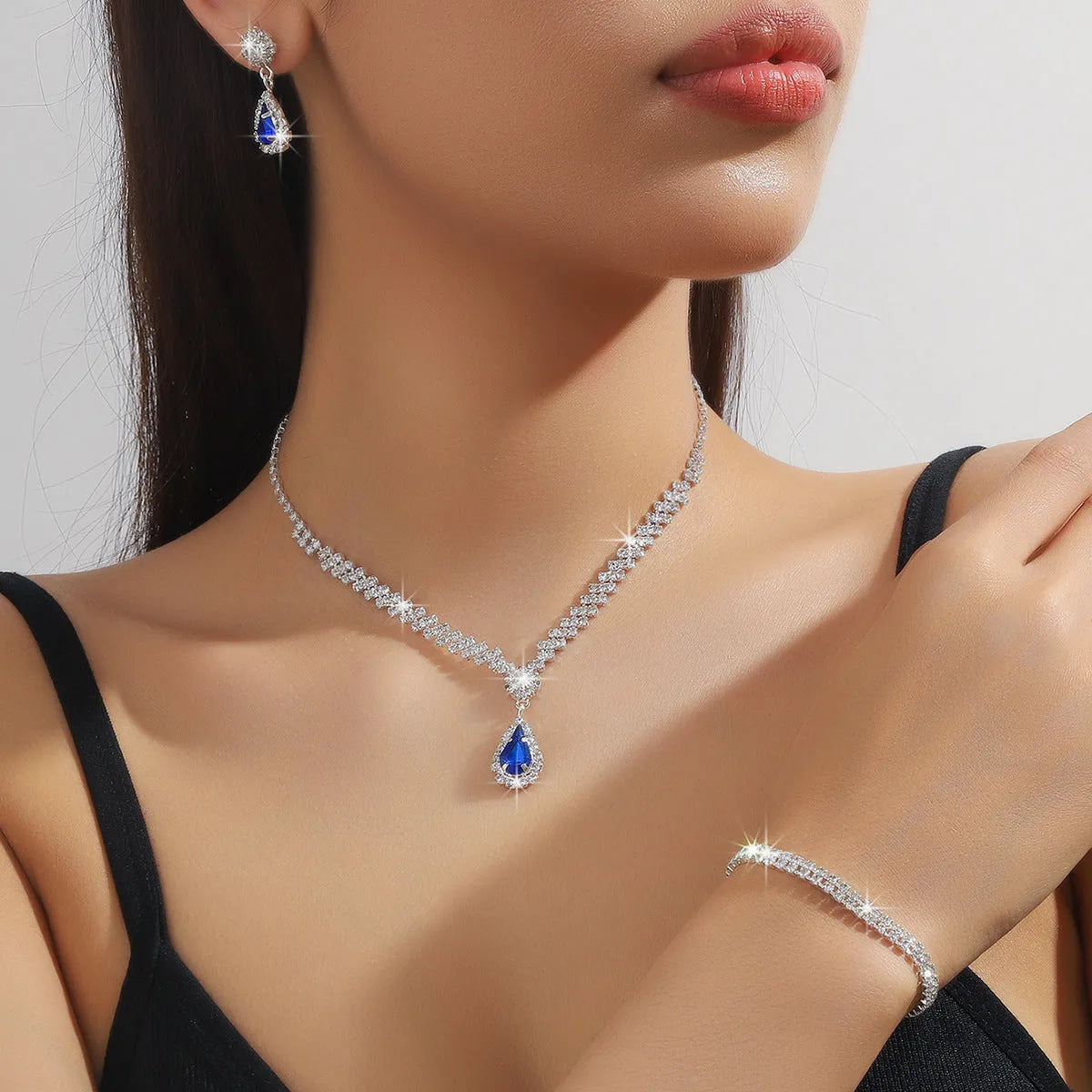 Claw chain necklace and matching earrings set with drop-shaped rhinestones in blue colour