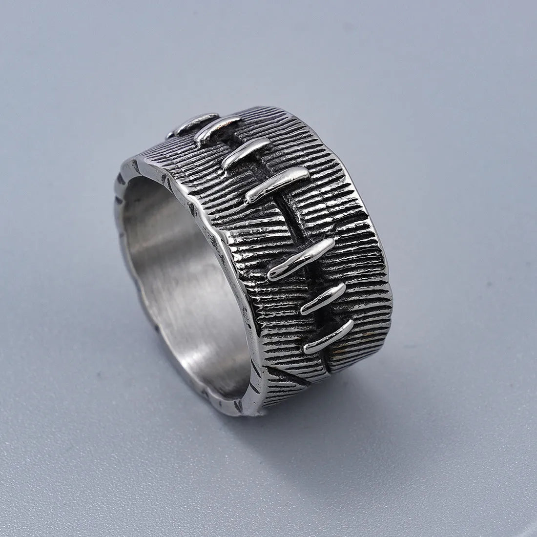 Geometric dark punk double ring in titanium steel on a black background, showing its U-shaped silhouette.