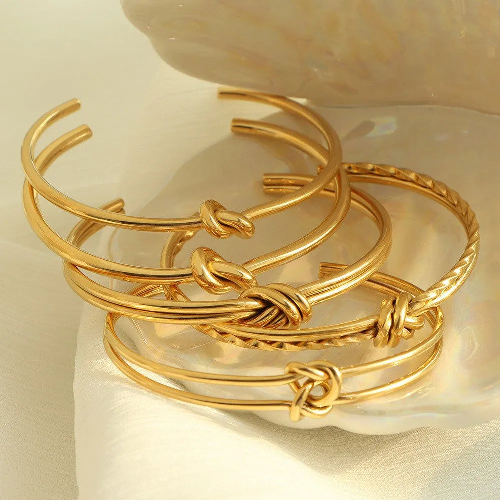 Women's stainless steel C-shaped knotted open bracelet with gold or silver electroplated finish.