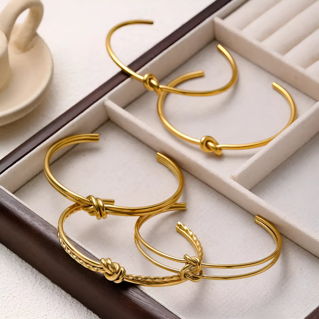 Women's stainless steel C-shaped knotted open bracelet with gold or silver electroplated finish.