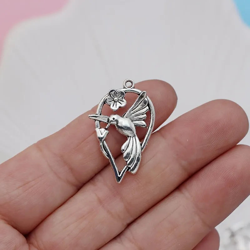 Close-up of an alloy pendant charm featuring a detailed magpie or cuckoo bird design with an electroplated finish.