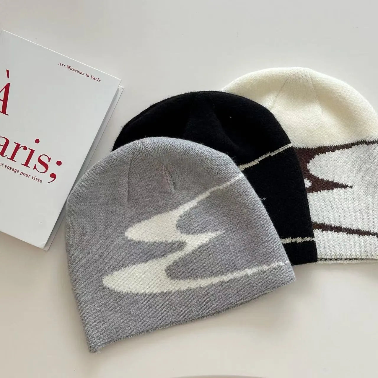 A knitted acrylic beanie hat in medium size, shown in black, grey, and white colour options.