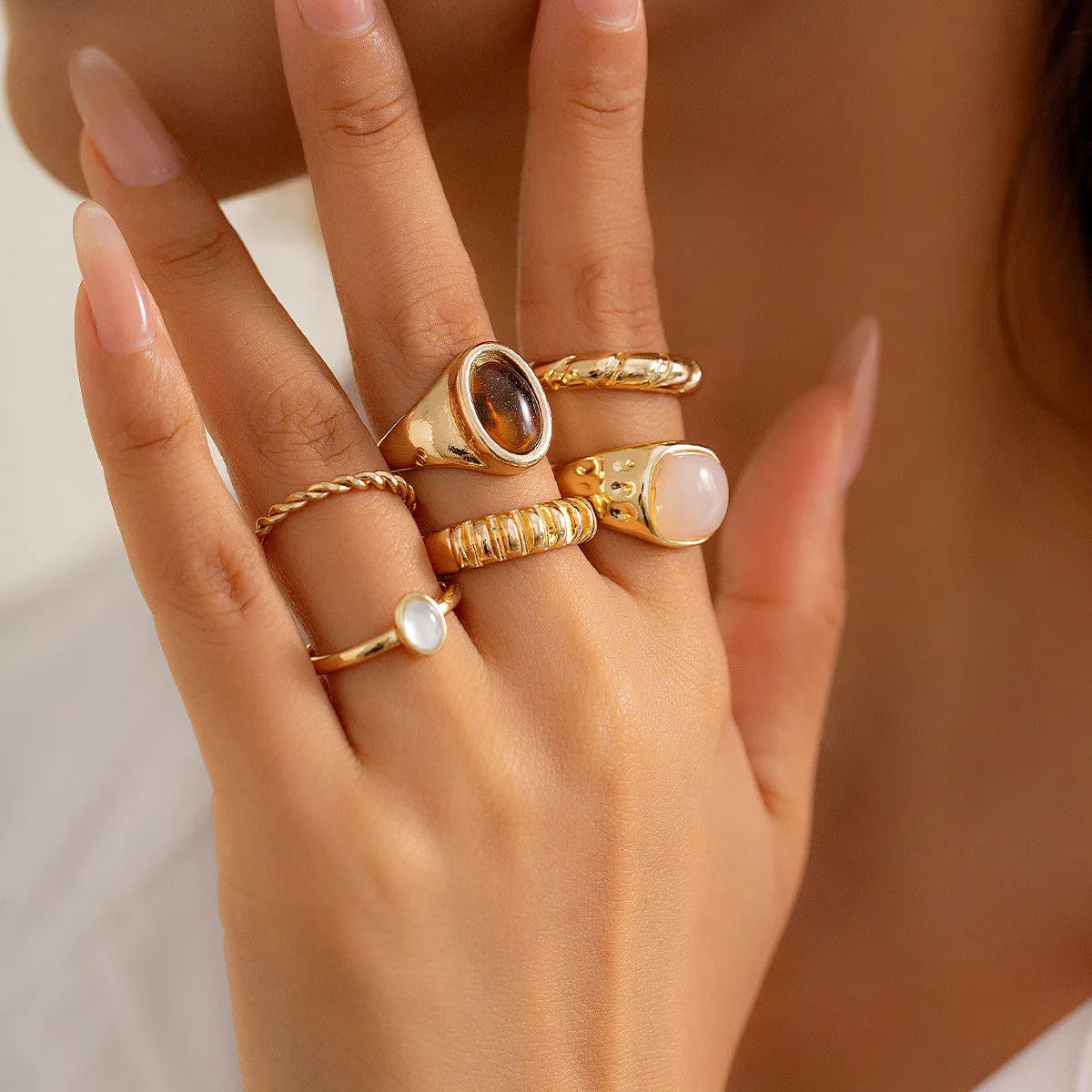 Six geometric alloy rings in light gold finish arranged for display