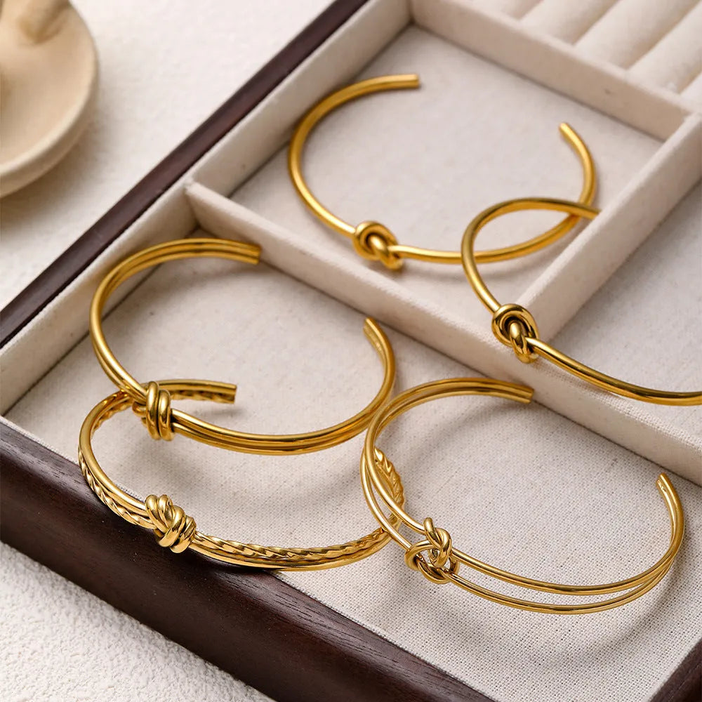 Women's stainless steel C-shaped knotted open bracelet with gold or silver electroplated finish.