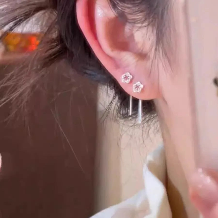 A pair of silver-coloured alloy hanging earrings with a hollow floral stud design.