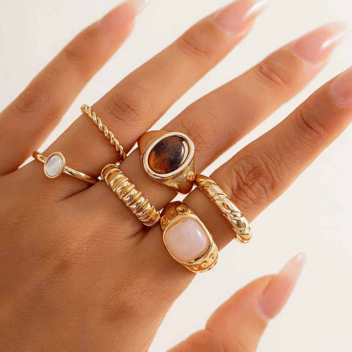 Six geometric alloy rings in light gold finish arranged for display