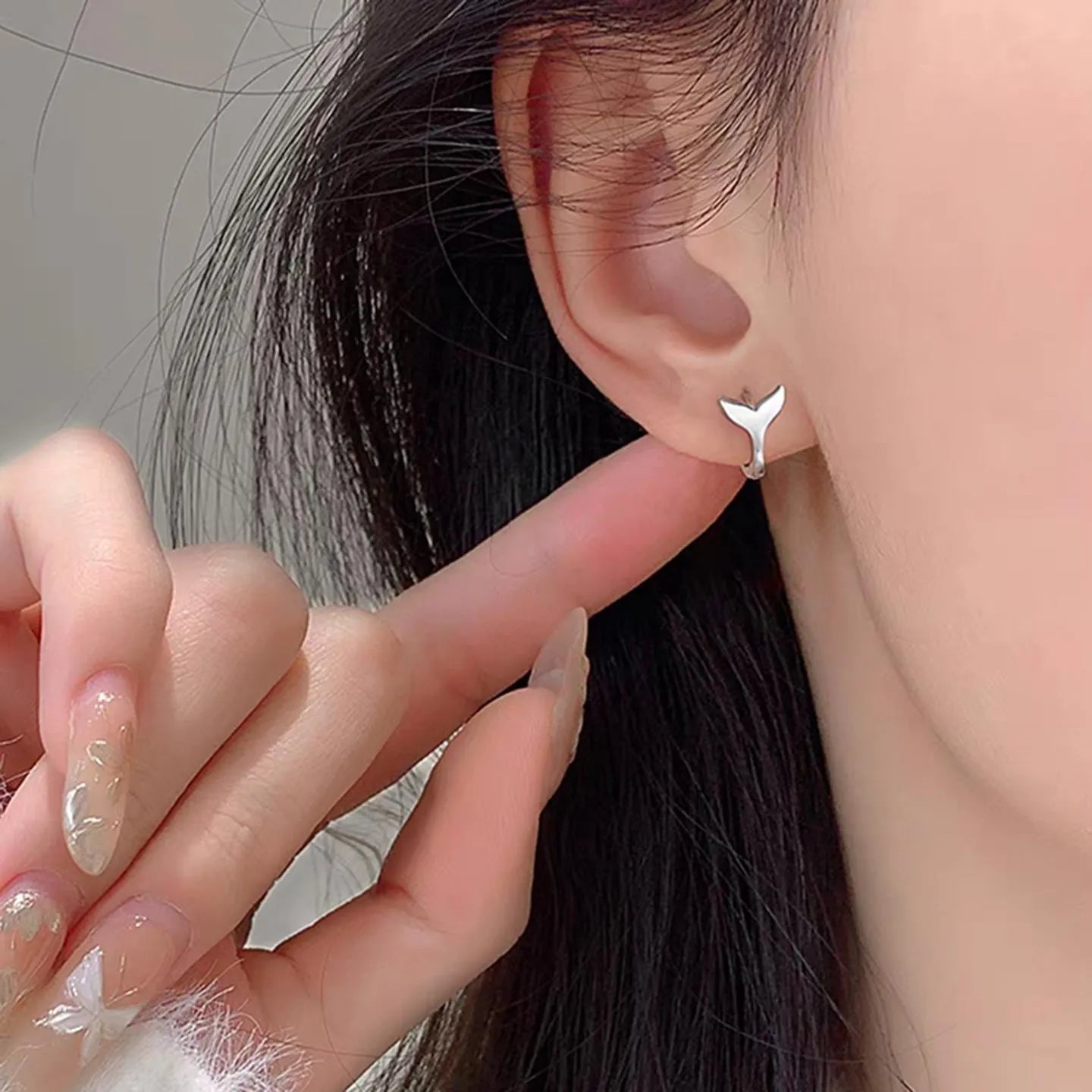 A pair of women's fishtail design earrings in copper with a white gold or yellow gold electroplated finish.
