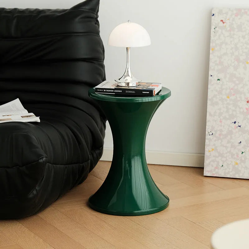 Plastic hourglass-style shoe changing stool in green, shown in a home entryway.