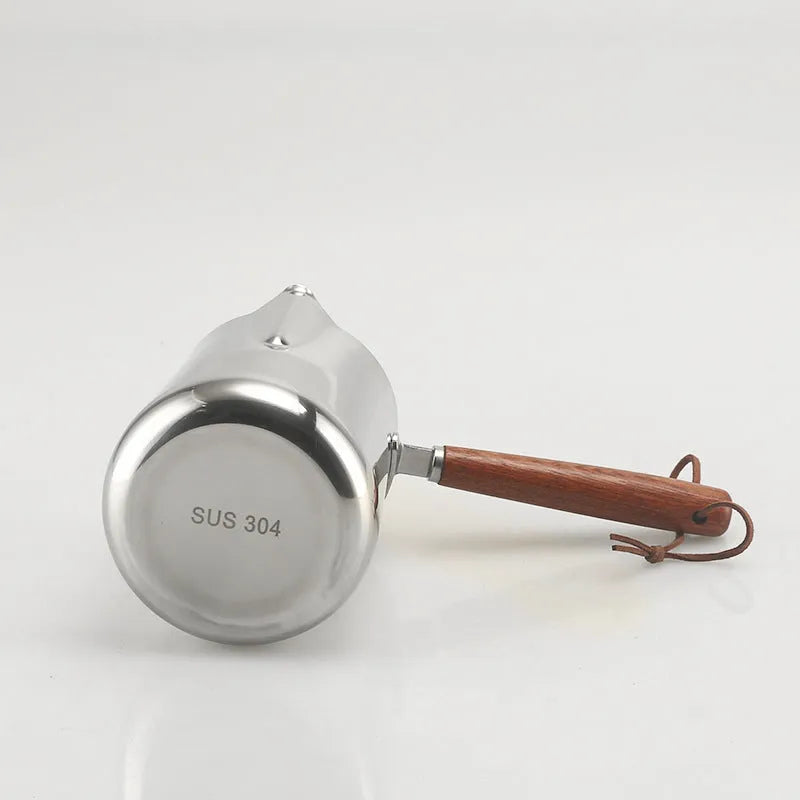 Stainless steel milk jug with measurement scale and wooden handle for barista latte art.
