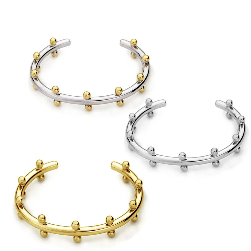 Stainless steel C-shaped charm with textured rivet bean beads on a round alloy bracelet.