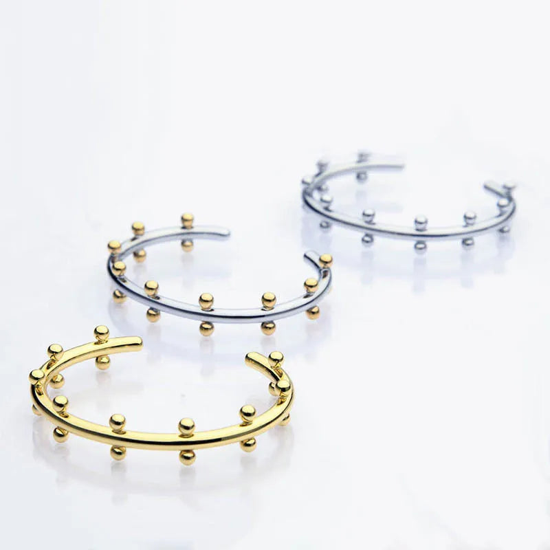 Stainless steel C-shaped charm with textured rivet bean beads on a round alloy bracelet.