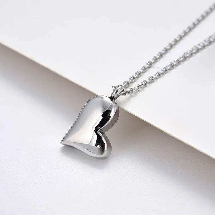 Silver-colour stainless steel necklace with a curved peach heart pendant on an adjustable chain.