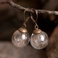 Transparent glass ball earrings with dandelion seed designs on French hooks in silver and bronze finishes