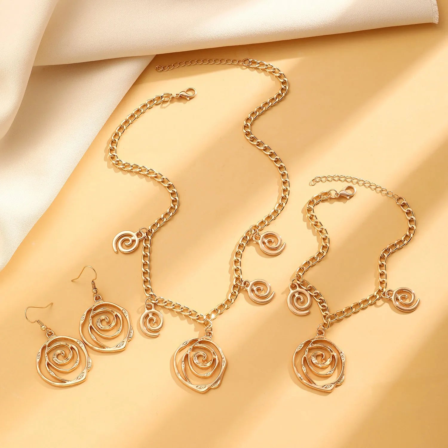 Spiral donut jewellery set showing necklace, bracelet and earrings in gold tone geometric circle design
