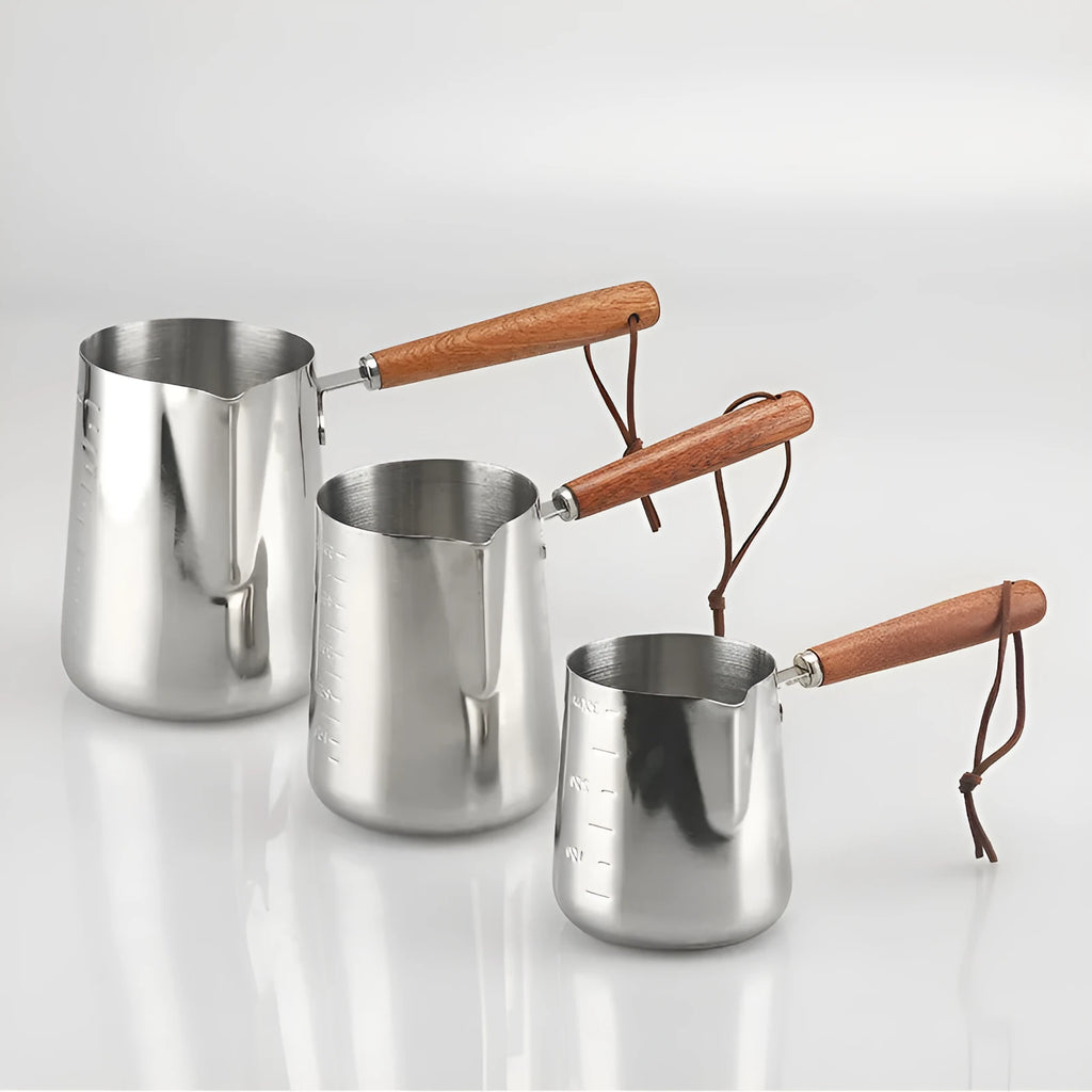 Stainless steel milk jug with measurement scale and wooden handle for barista latte art.