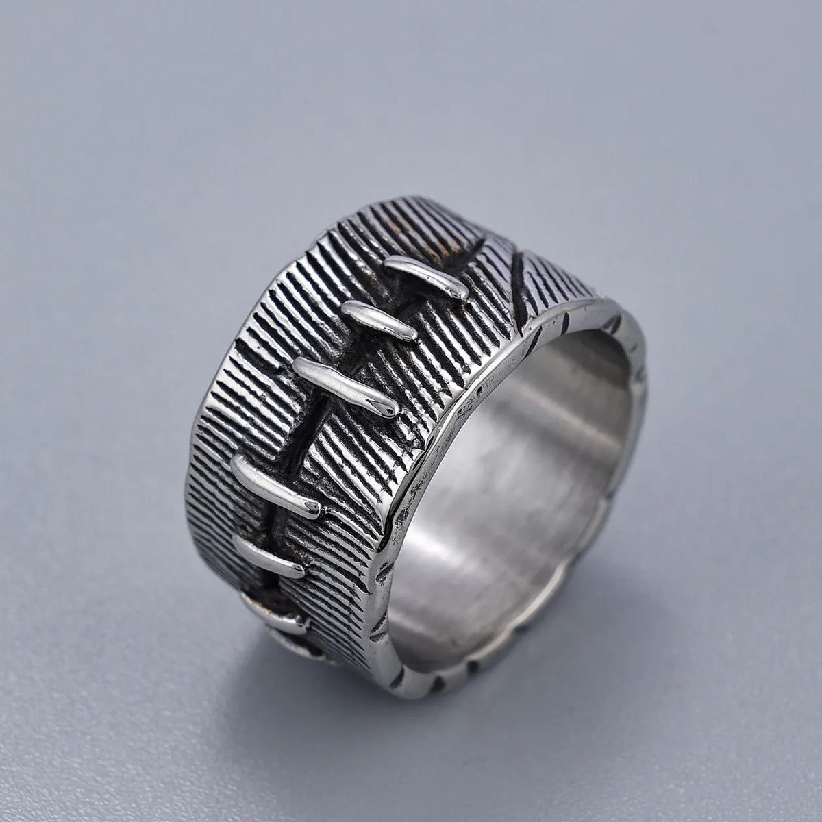 Geometric dark punk double ring in titanium steel on a black background, showing its U-shaped silhouette.