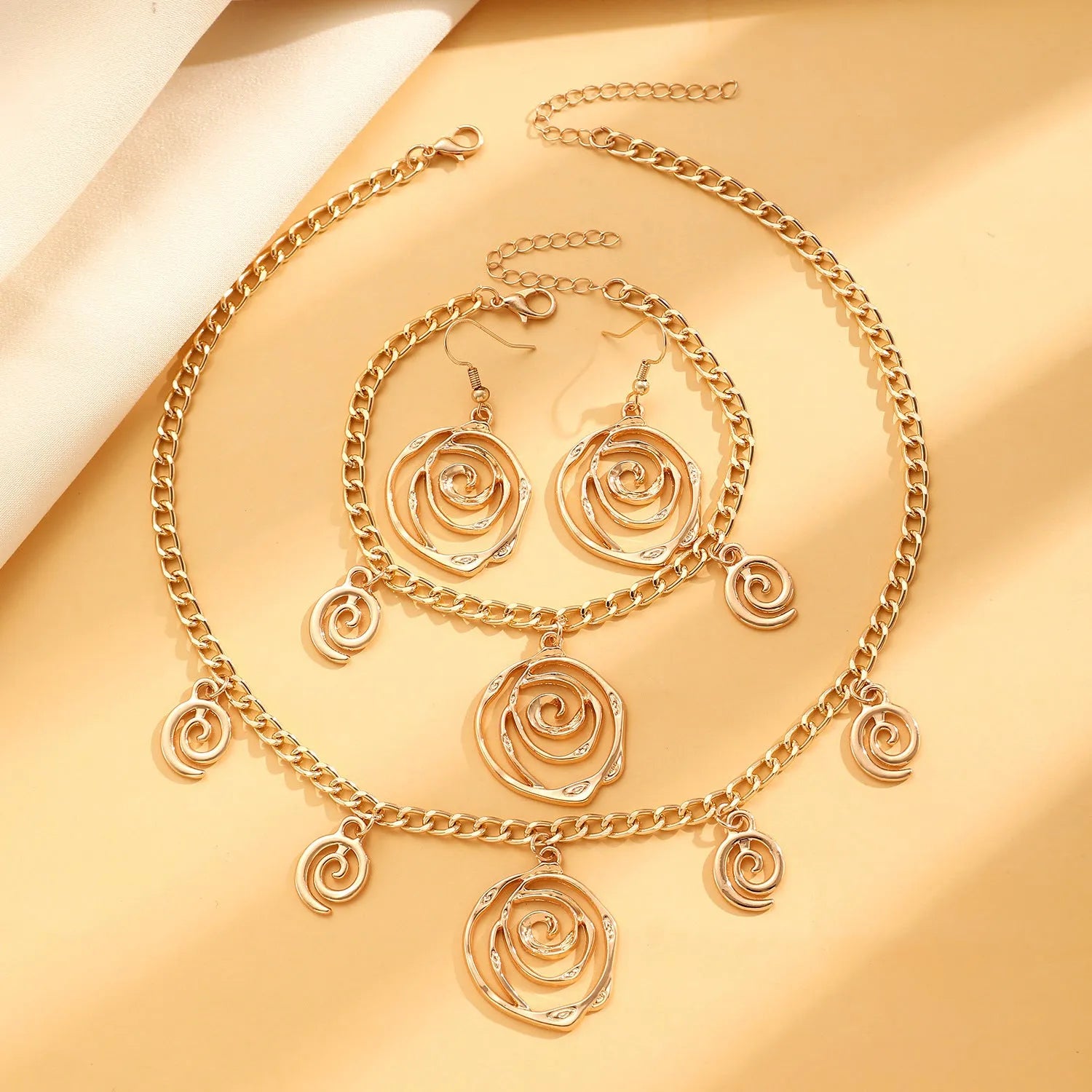 Spiral donut jewellery set showing necklace, bracelet and earrings in gold tone geometric circle design