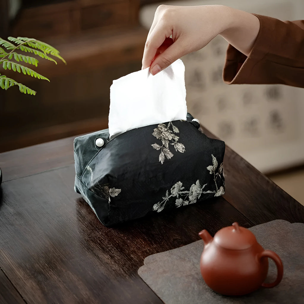 White Chinese brocade tissue box cover with embroidered plum blossoms, shown with and without a pearl buckle.
