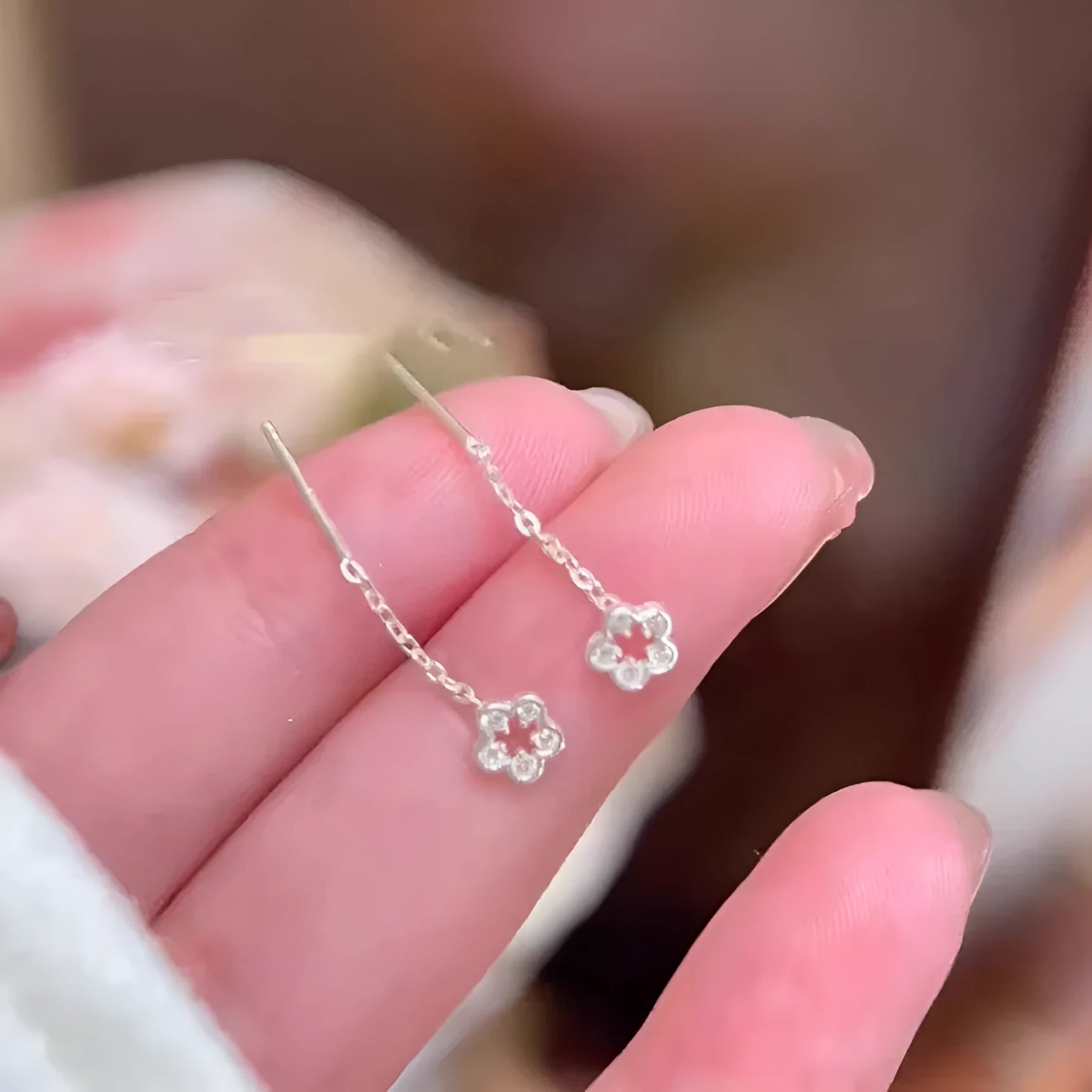 A pair of silver-coloured alloy hanging earrings with a hollow floral stud design.