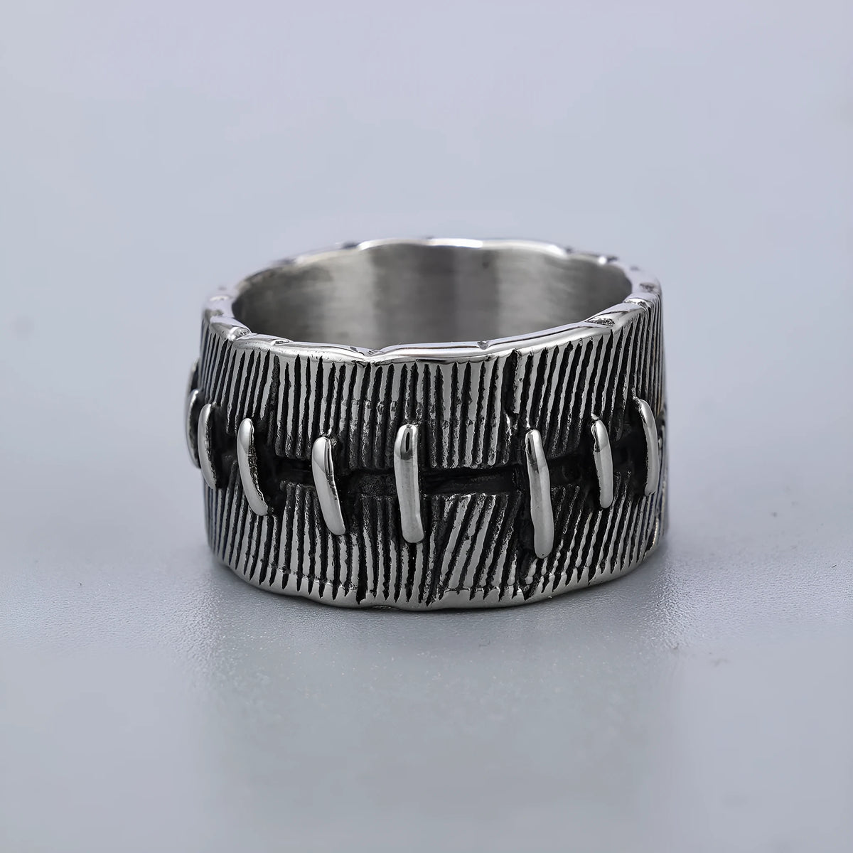 Geometric dark punk double ring in titanium steel on a black background, showing its U-shaped silhouette.