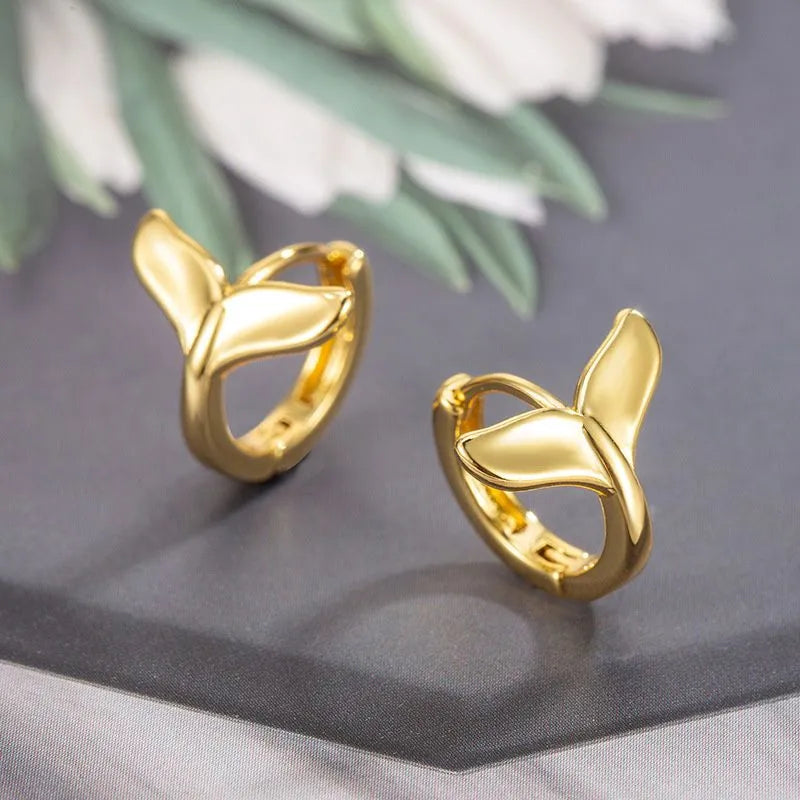 A pair of women's fishtail design earrings in copper with a white gold or yellow gold electroplated finish.