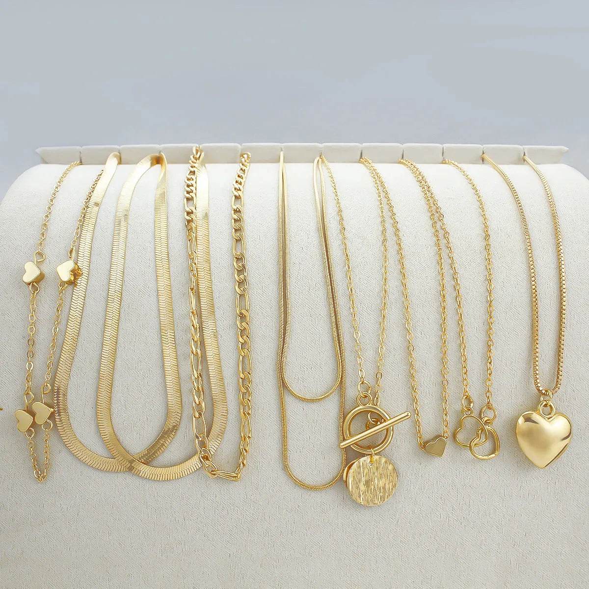 Ten gold-coloured women's necklaces with different alloy pendants on snake bone chains