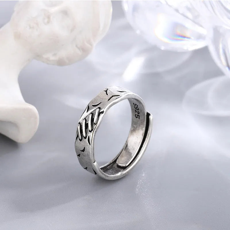 Black geometric copper ring with adjustable opening on a white background.