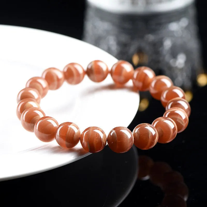 Natural old mine rhodochrosite round bead bracelet with ruyi design on a wrist.