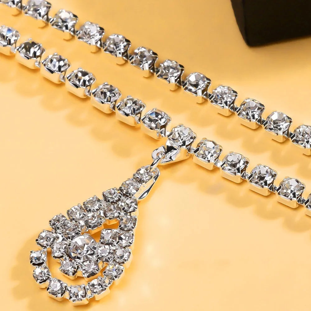Gold and silver waist chain with a water drop pendant and rhinestone details on a model.