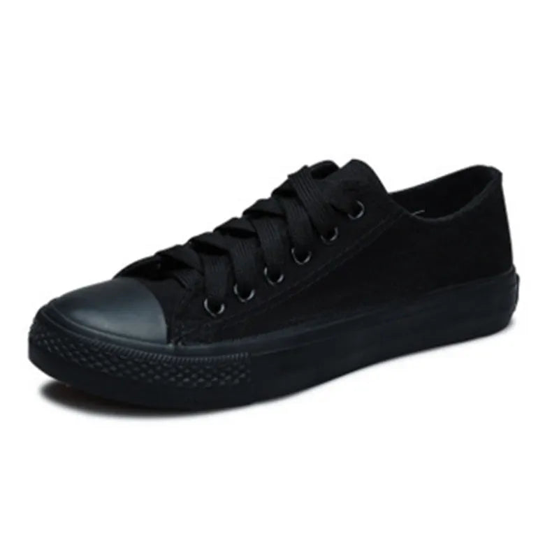 Women's solid-colour canvas shoes in black, shown on a foot from a side angle.
