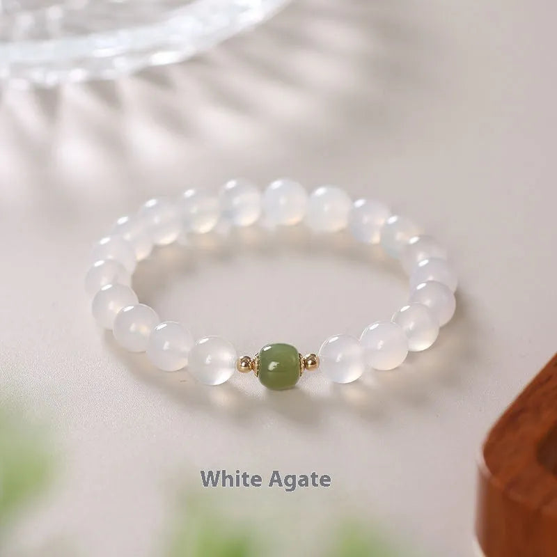Handmade white agate and Hetian jade crystal bracelet with cinnabar accents on a wrist.