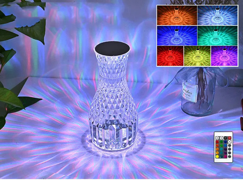 Transparent crystal vase shaped LED table lamp with remote control on a wooden bedside table.
