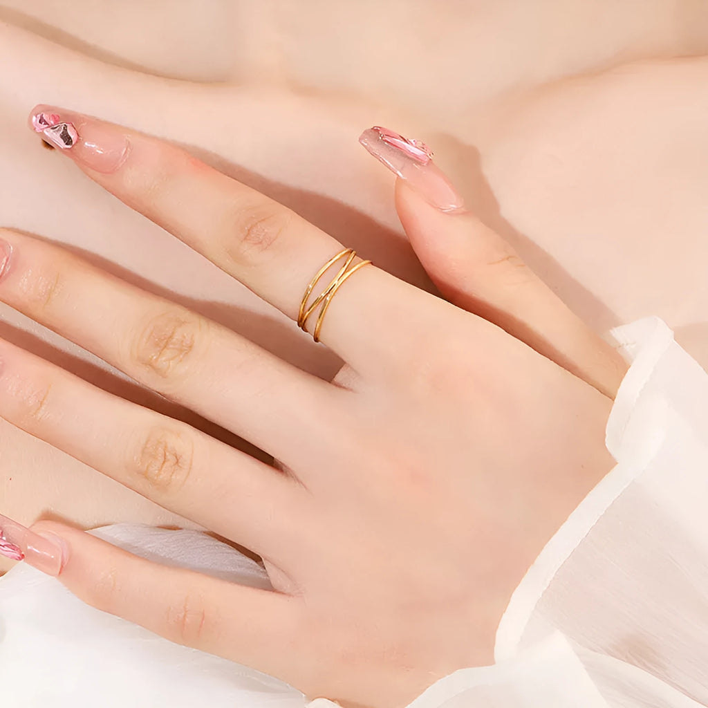 Geometric three-layer coil gold ring on a finger, showing titanium steel construction.