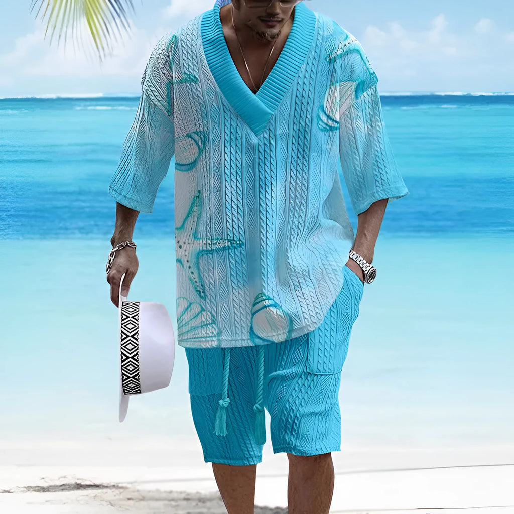 Man wearing a loose fit light blue short sleeve lounge top and matching shorts on a sofa.