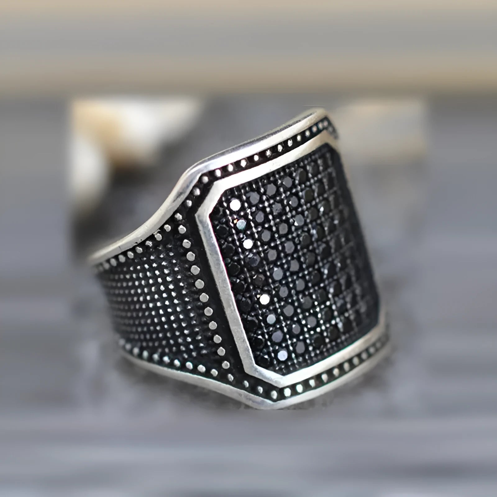 Black alloy ring with copper inlay and zircon stone details, shown on a finger.