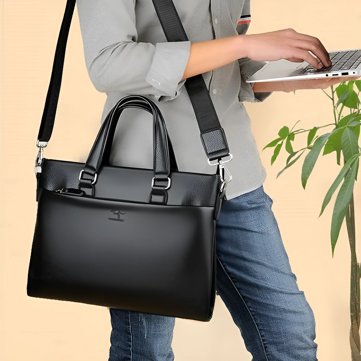 Men's black PU leather shoulder messenger bag with splicing design on a table.