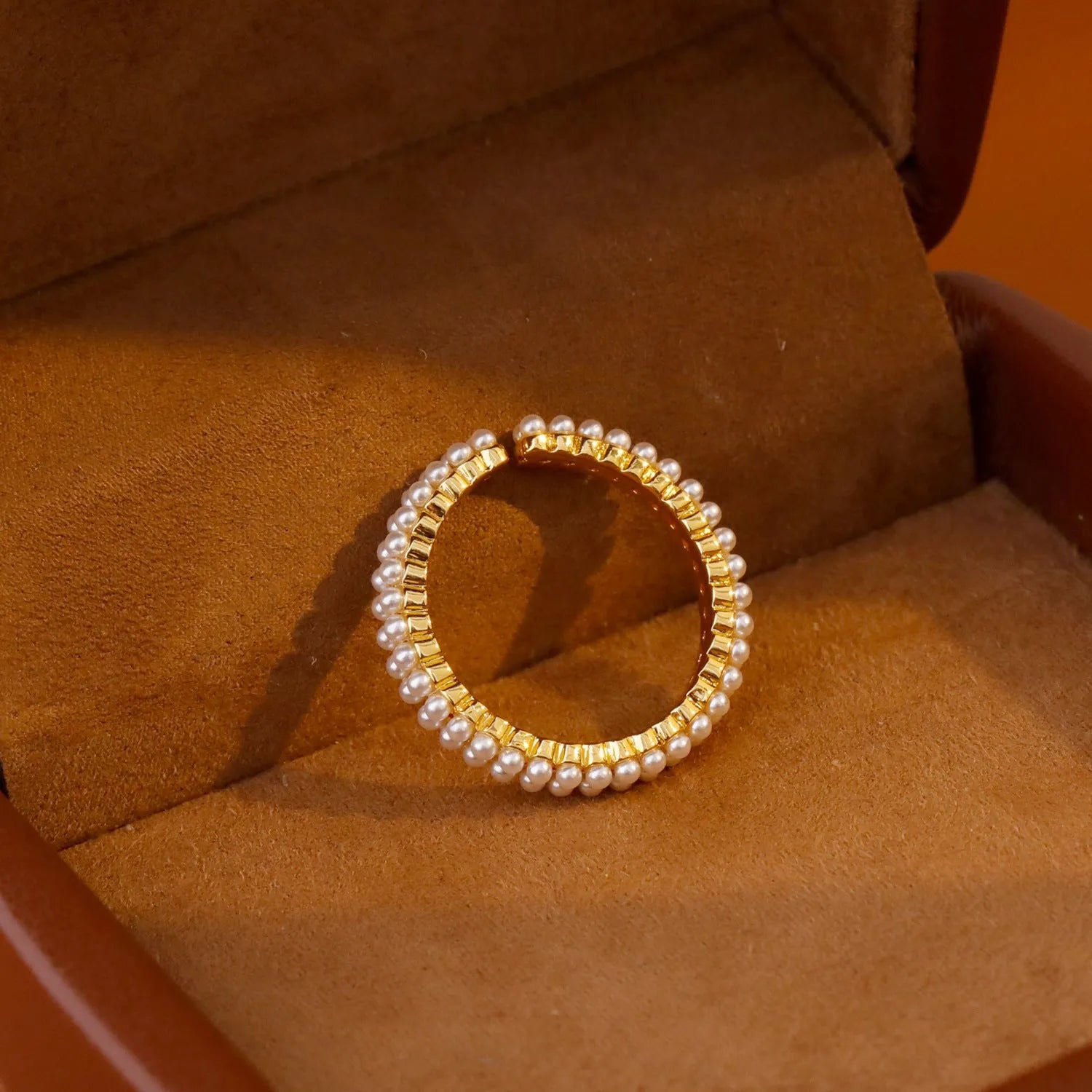 Gold geometric open ring with pearl detail on a model's finger.